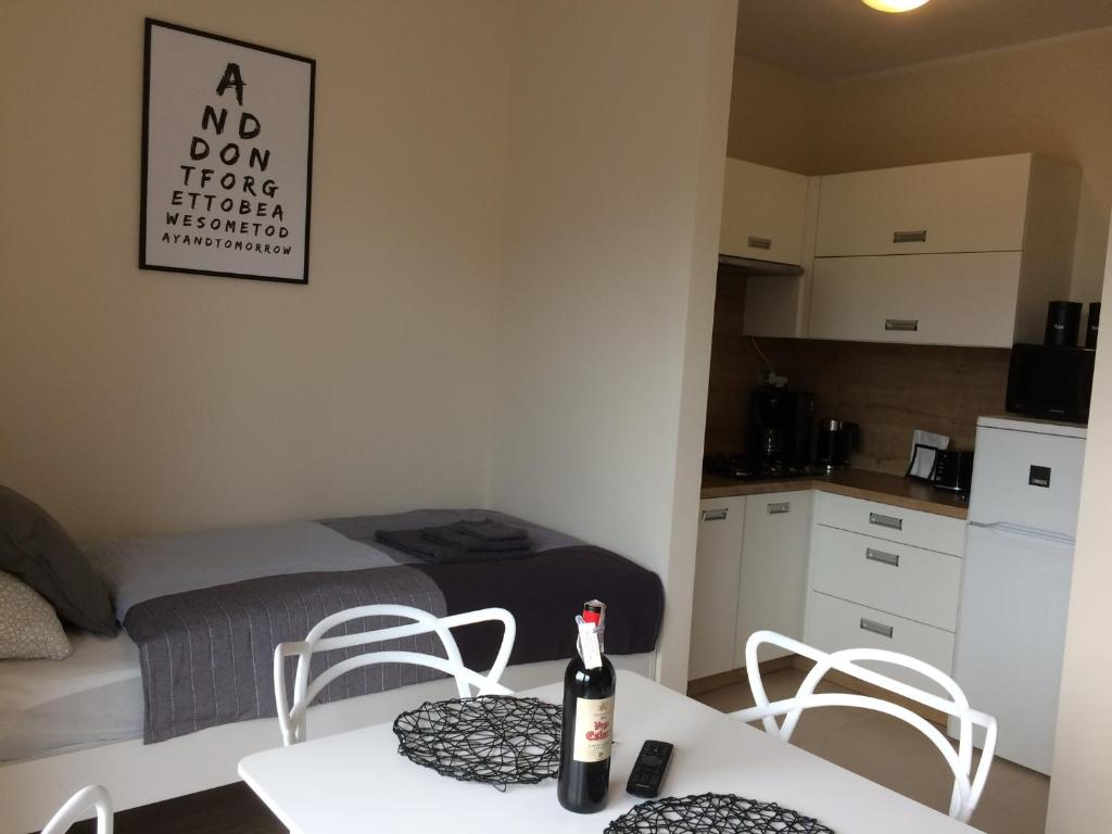 Una habitación con una cama y una mesa con una botella. en Apartament Fibra Latte en Rybnik