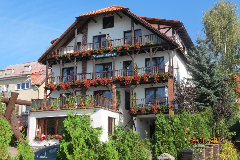 ein weißes Gebäude mit Blumen auf den Balkonen in der Unterkunft Pensjonat Mikołajki in Mikołajki