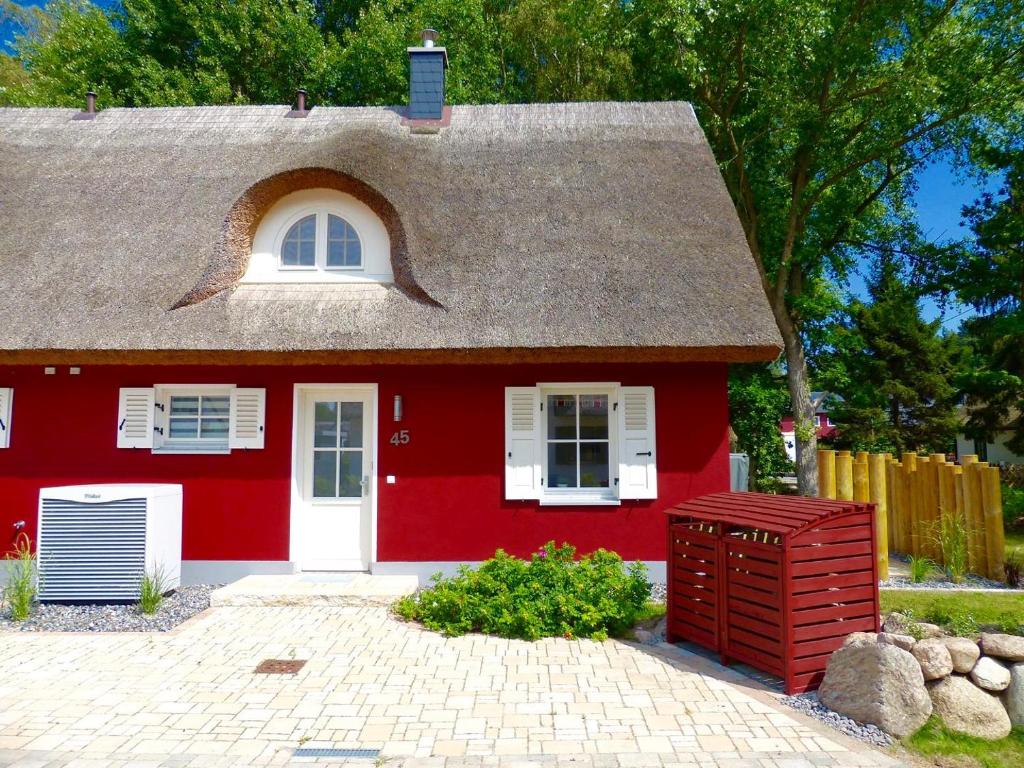 ein rotes Haus mit einem grauen Dach und einer weißen Tür in der Unterkunft Ferienhaus Stella in Glowe