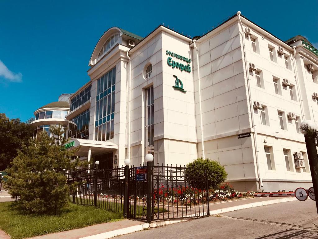 a white building with a sign on the front of it at Hotel Erofey in Khabarovsk