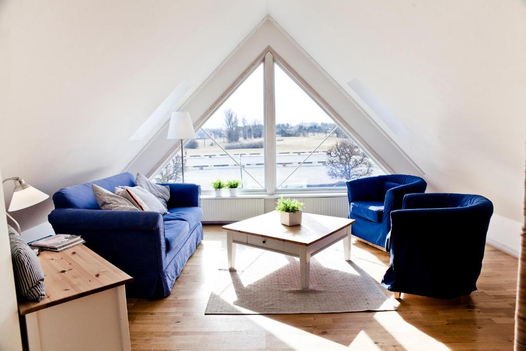 a living room with blue couches and a large window at Abbekås Golfrestaurang & Hotell in Abbekås