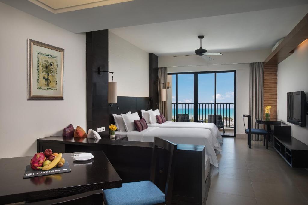 a large hotel room with a bed and a view of the ocean at Ramada Plaza by Wyndham Sanya Bay in Sanya