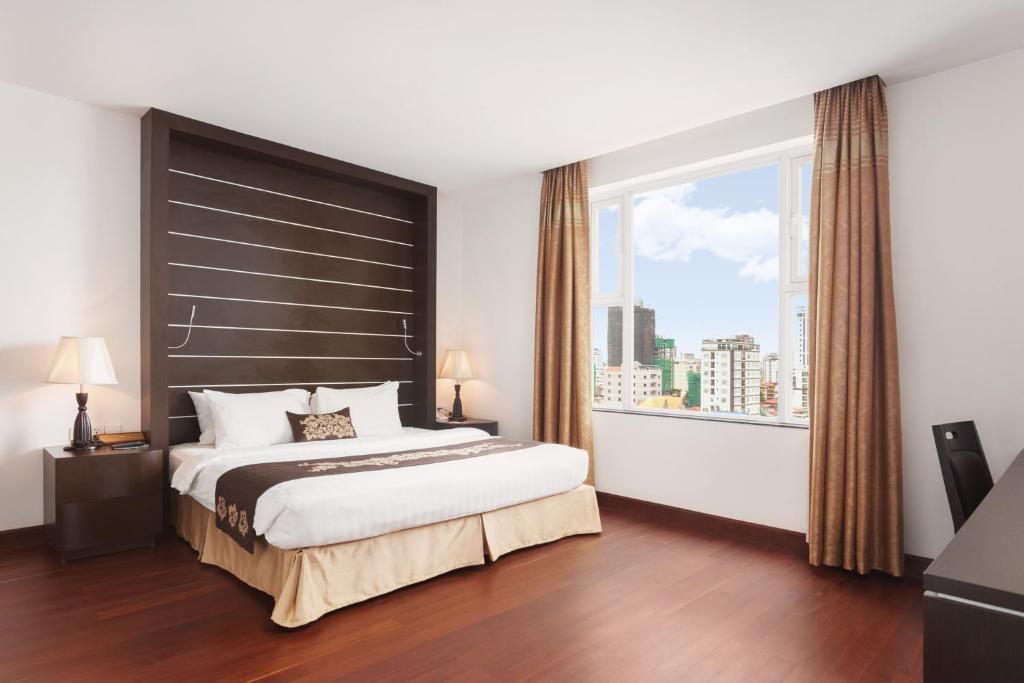 a bedroom with a large bed and a large window at Phnom Penh Katari Hotel in Phnom Penh