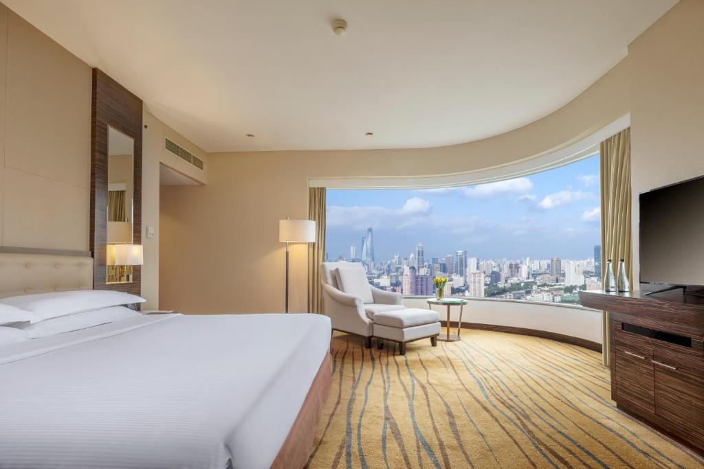 een hotelkamer met een groot bed en een groot raam bij The Kunlun Jing An in Shanghai