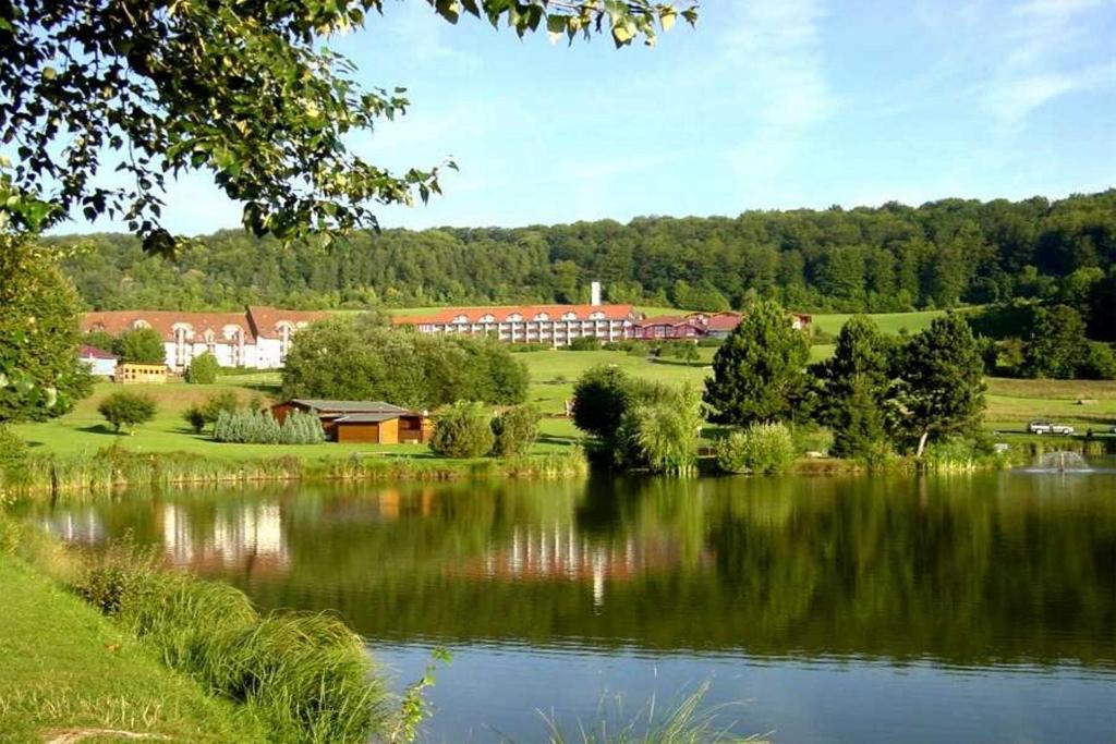 a view of a lake with buildings in the background at Hessen Hotelpark Hohenroda in Hohenroda