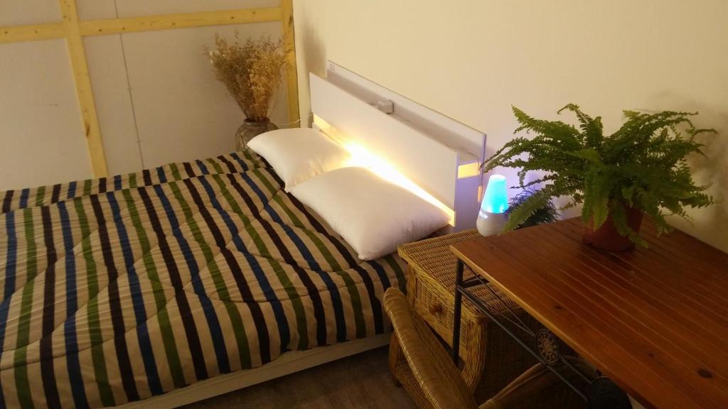 清水區的住宿－岸渡陳艙，一间卧室配有一张床和一张植物桌子