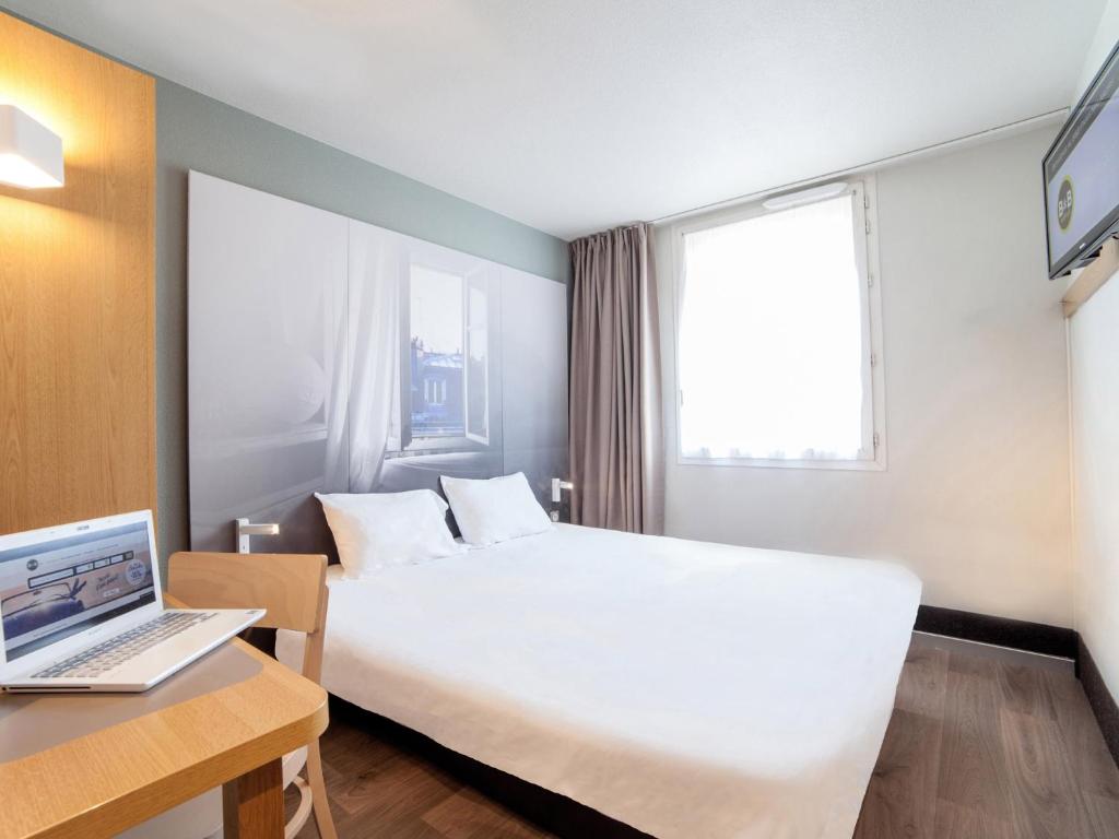 ein Hotelzimmer mit einem Bett und einem Laptop auf dem Schreibtisch in der Unterkunft B&B HOTEL Orleans Saint-Jean de Braye in Saint-Jean-de-Braye