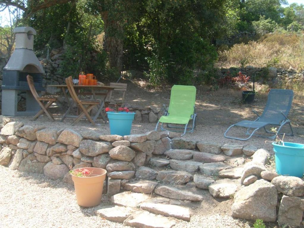 two chairs and a table and a stone wall at Gîte à Piscia de Figari Petru Barbara in Figari