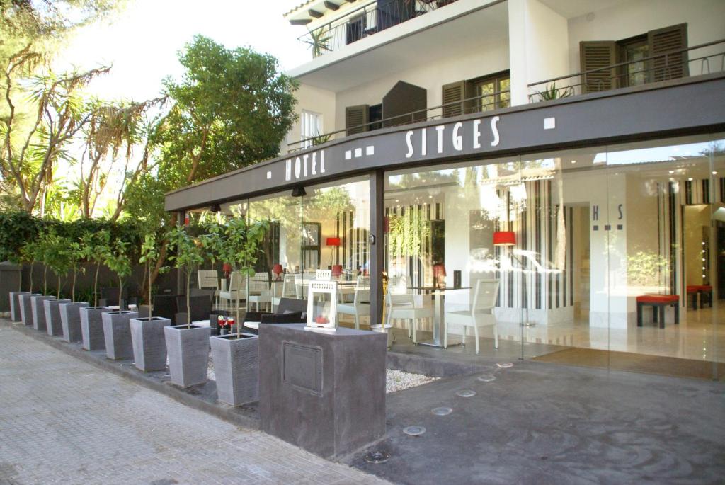Hotel Sitges في سيتجيس: متجر أمام مبنى به طاولات وكراسي