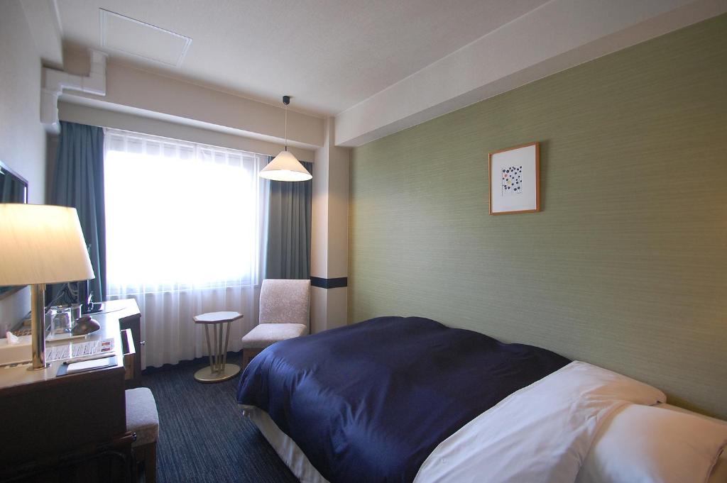 岡山市にあるホテルエクセル岡山のベッドと窓が備わるホテルルーム