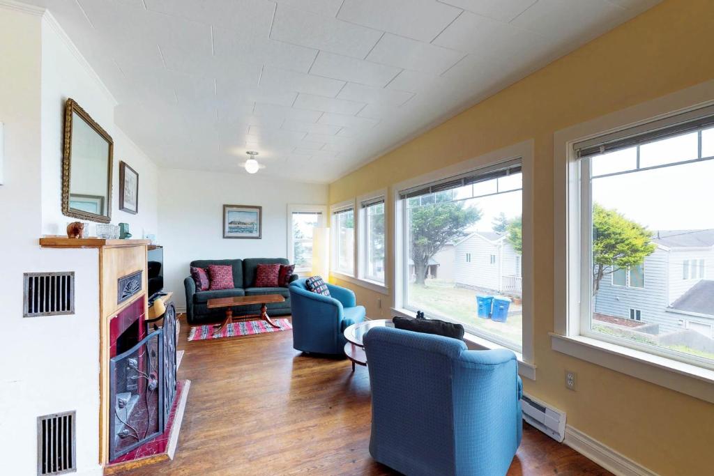 a living room with blue chairs and windows at Whale - Watcher's Perch in Depoe Bay