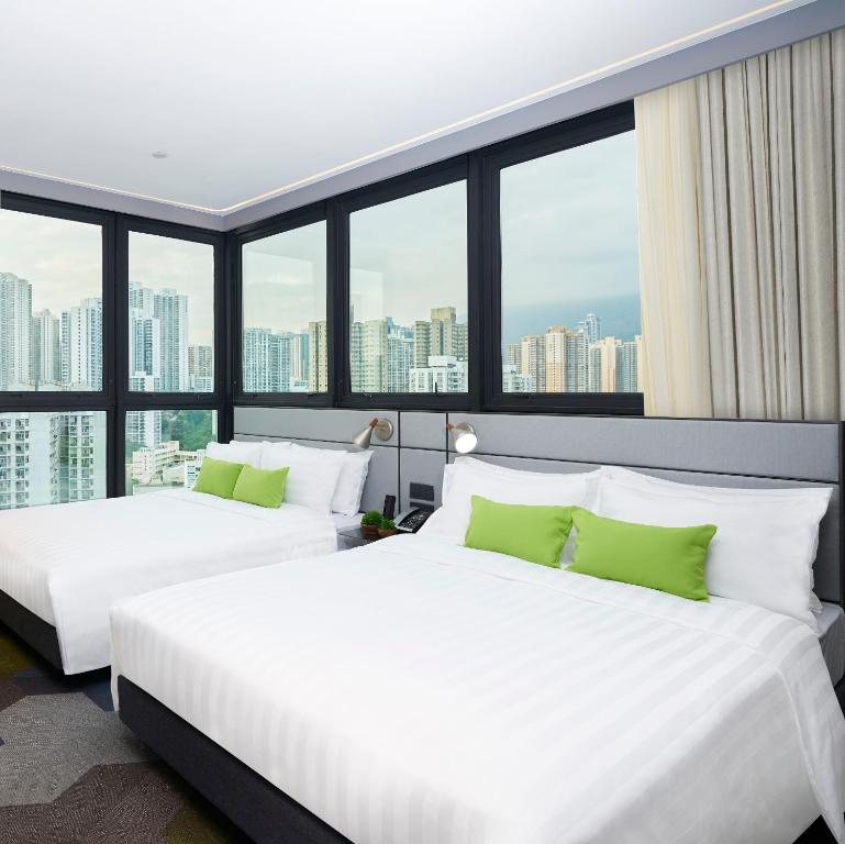 two beds in a hotel room with large windows at Hotel Ease Access Tsuen Wan in Hong Kong