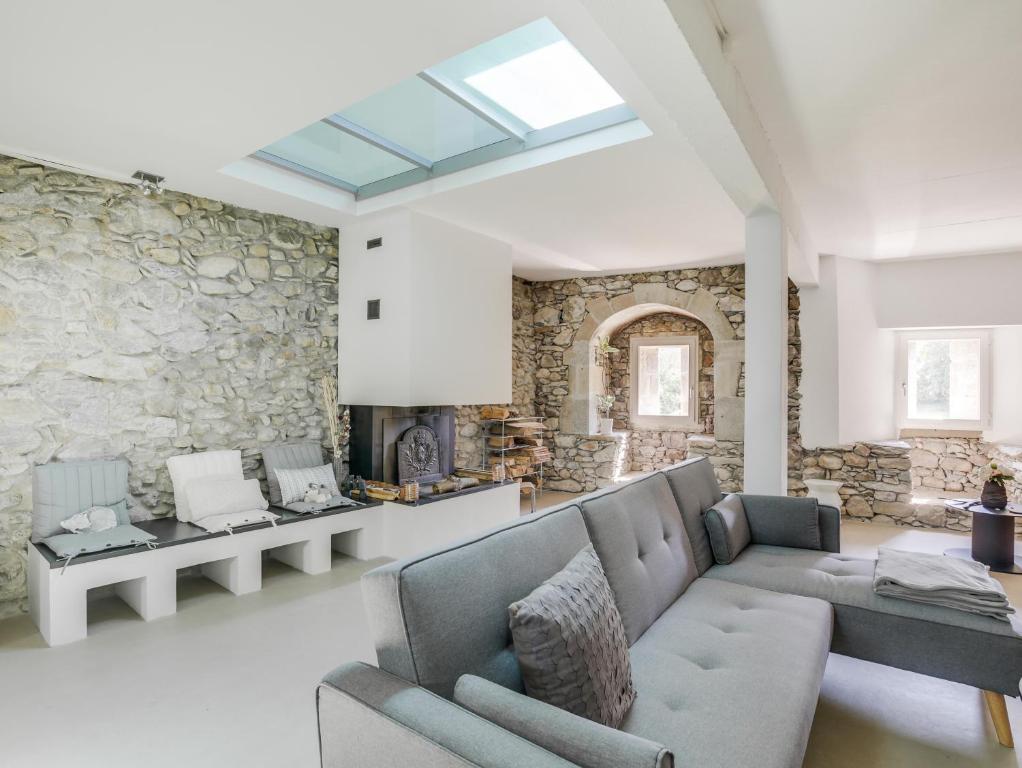 a living room with a couch and a stone wall at Le Loft de Rovorée in Yvoire