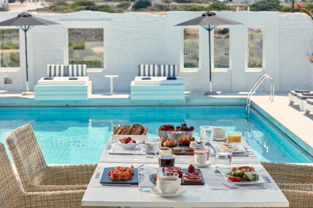 a table with breakfast food next to a swimming pool at Mrs. Armelina by Mr&Mrs White Hotels in Naousa