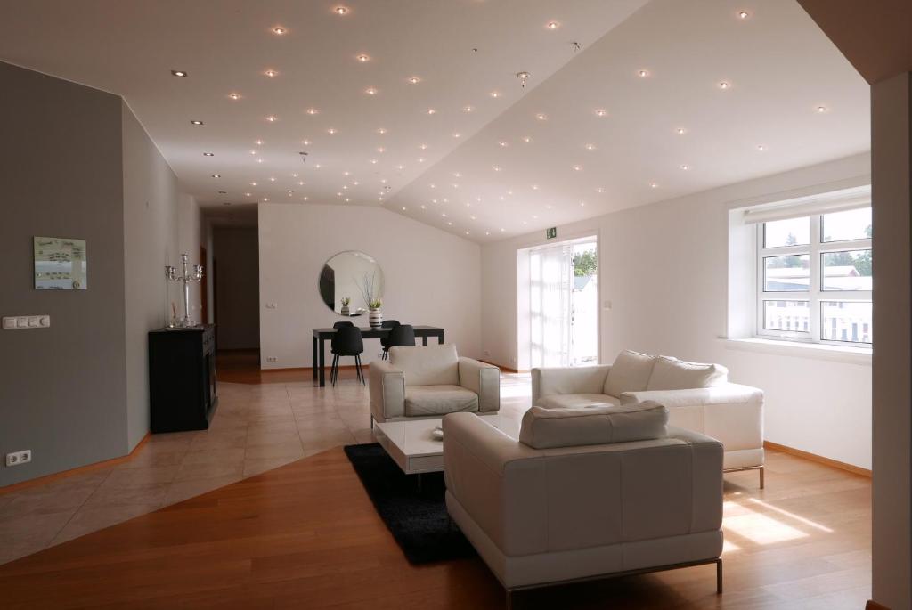 sala de estar con muebles blancos y techo con luces. en Askja Apartment, en Húsavík