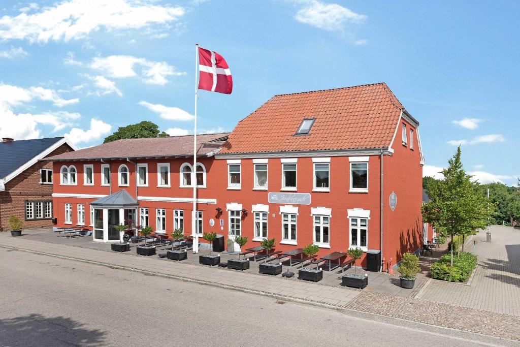 un bâtiment rouge avec un drapeau en haut dans l'établissement Hotel Jernbanegade, à Kibæk