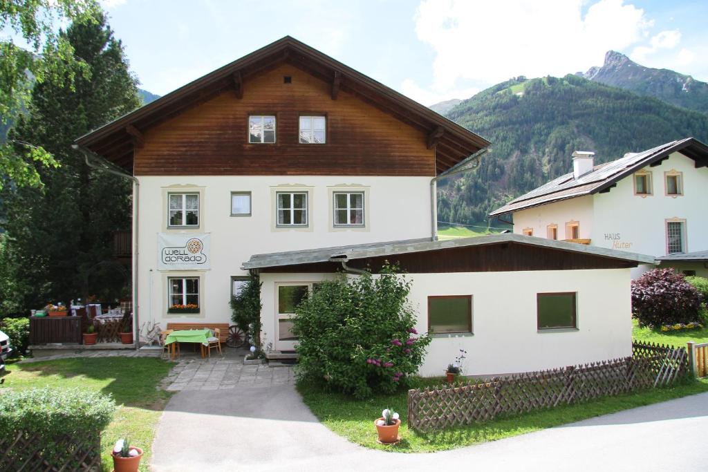 uma grande casa branca com um telhado de madeira em well-dorado em Kals am Grossglockner