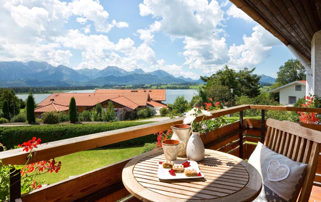 a table on a balcony with a view of a lake at Hotel Alpenglühn in Füssen