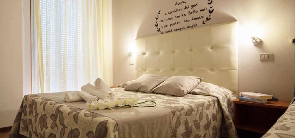 a bedroom with a bed with white sheets and flowers on it at Hotel Sandra in Rimini