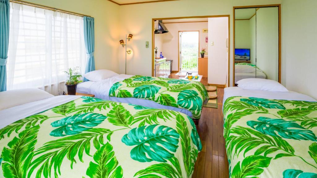 a hotel room with three beds with green leaves at Hotel Sunset ZANPA in Yomitan