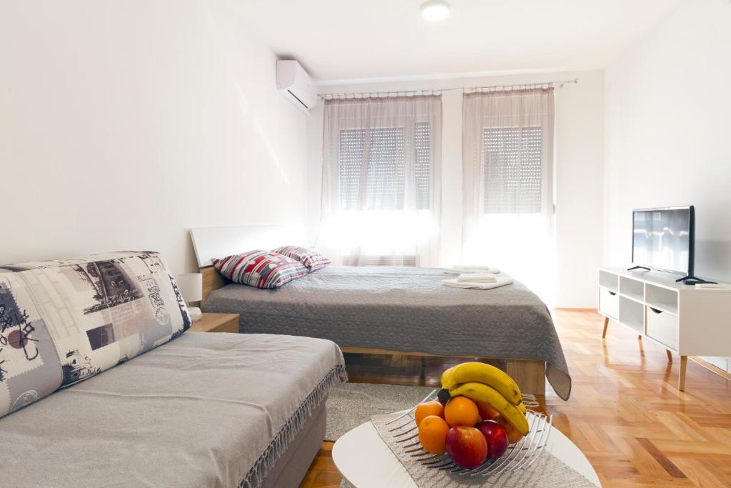 a living room with two beds and a table with fruit on it at Tea Studio Apartments in Niš