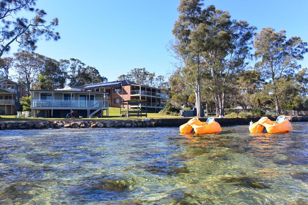 three inflatable boats in the water in front of a building at Dungowan Holiday Accommodation in Erowal Bay
