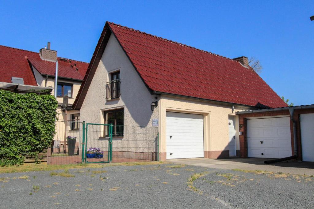 ein Haus mit zwei Garagentüren und einem roten Dach in der Unterkunft Ferienwohnung Sperlingslust in Niepars