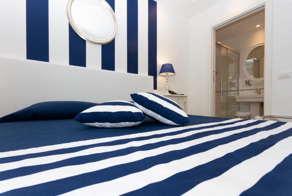 a bed with blue and white striped sheets and pillows at Hotel Nautilus in Cagliari
