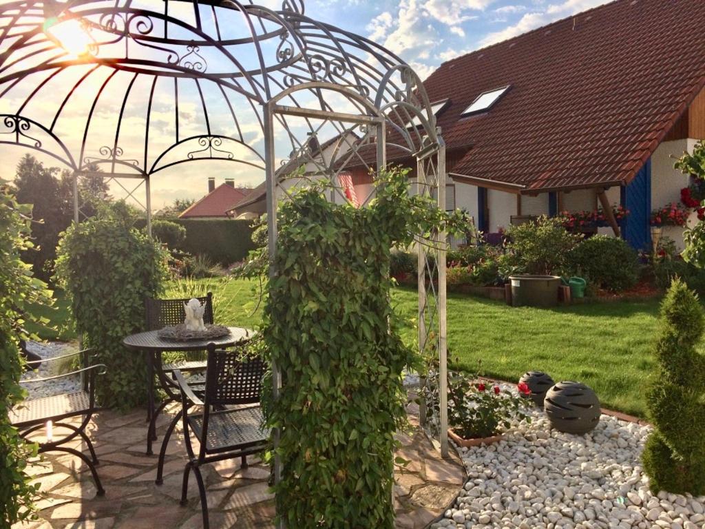 a garden with a pergola and a table and chairs at Ferienwohnung Evelyn und Reinhard Himmler in Pleinfeld