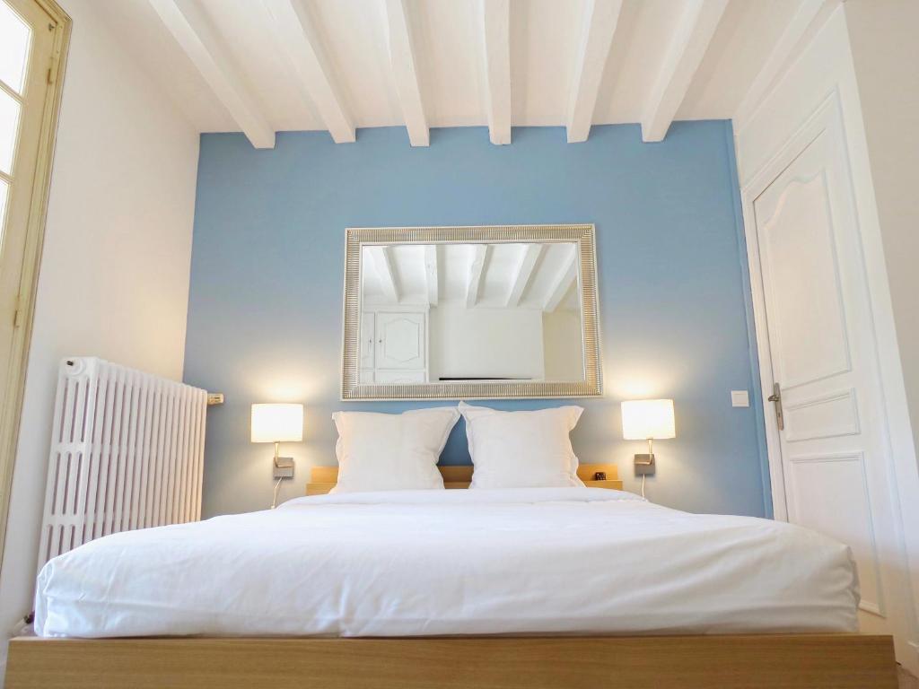 una camera con un letto bianco e una parete blu di Les Chambres Lune a Saint-Aignan
