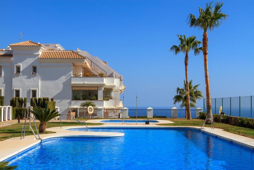 a swimming pool in front of a house with palm trees at Aaron in Rincón de la Victoria