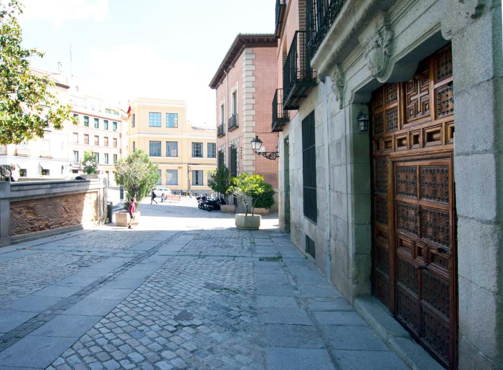 una calle vacía con un edificio con una puerta de madera en Plaza de Carros, 3, en Madrid