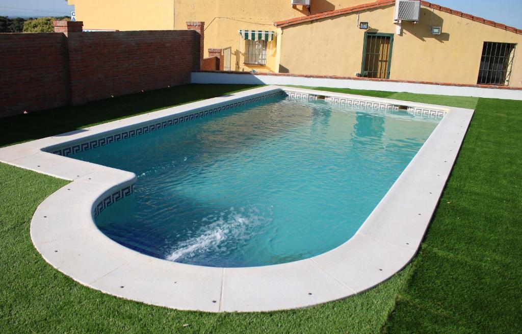 una piscina en un patio con césped verde en Pilar Casa Rural, en Trujillo