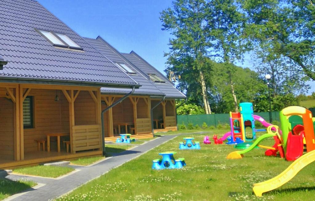 um quintal com uma casa com um parque infantil e um edifício em Nadmorski Skarb Domki Apartamentowe em Ostrowo