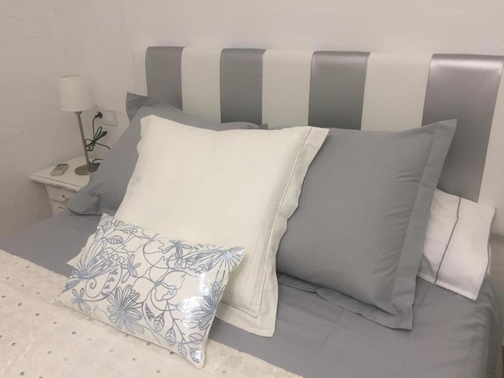 a bed with white pillows and a gray headboard at La Casa de la Higuerita in Fuengirola