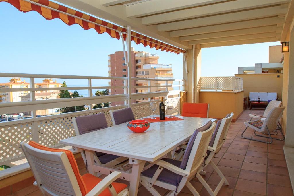 einen Tisch mit Stühlen und eine Flasche Wein auf dem Balkon in der Unterkunft Penthouse Ana in Algarrobo