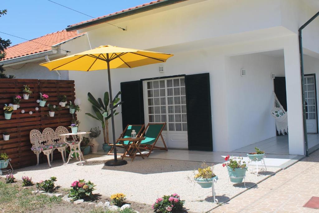 eine Terrasse mit einem Sonnenschirm, Stühlen und einem Tisch in der Unterkunft Casa das Camélias in Aveiro