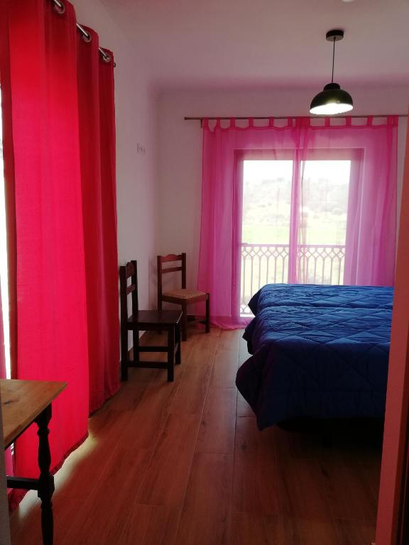 a bedroom with pink curtains and a bed and a window at Sol Mar in Odeceixe