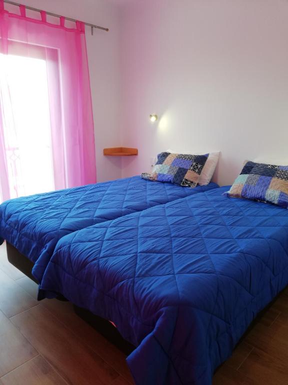 a blue bed in a room with a window at Sol Mar in Odeceixe