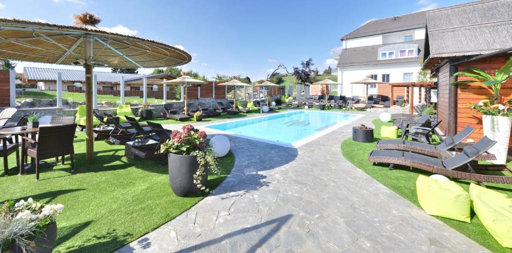 a swimming pool with lounge chairs and a table at Vakantiehotel Der Brabander in Winterberg