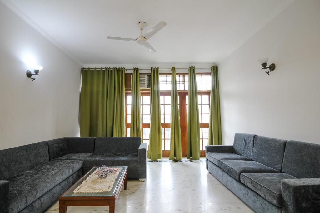 ein Wohnzimmer mit 2 Sofas und einem Tisch in der Unterkunft Under My Roof Green Park in Neu-Delhi