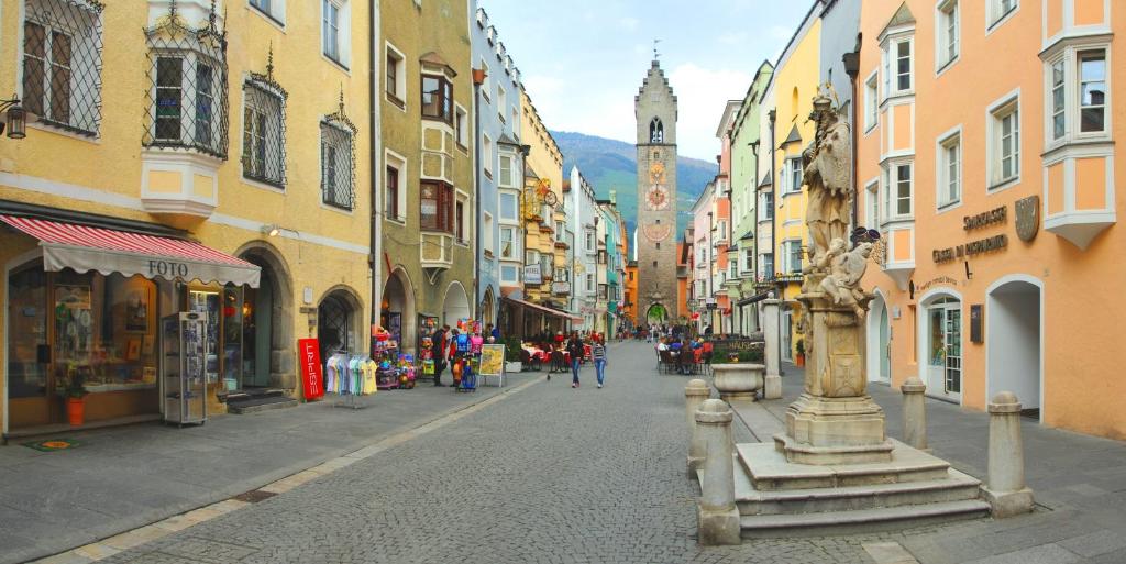 eine Stadtstraße mit Gebäuden und einem Uhrturm in der Unterkunft Appartamentino Frundsberg in Sterzing