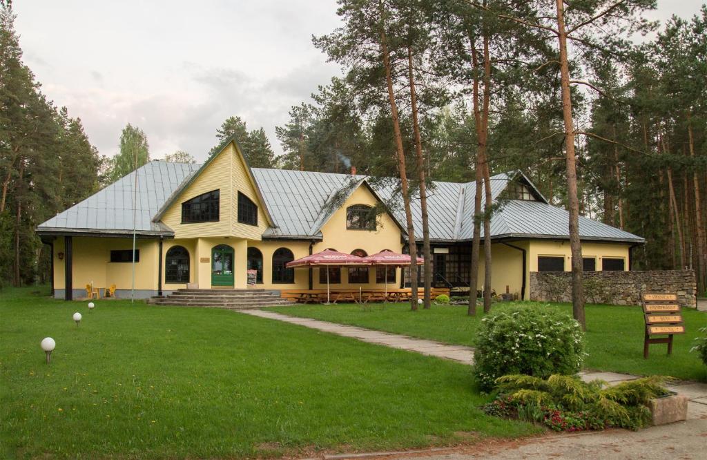 a yellow house with a gray roof on a yard at Motel Brencis in Iecava