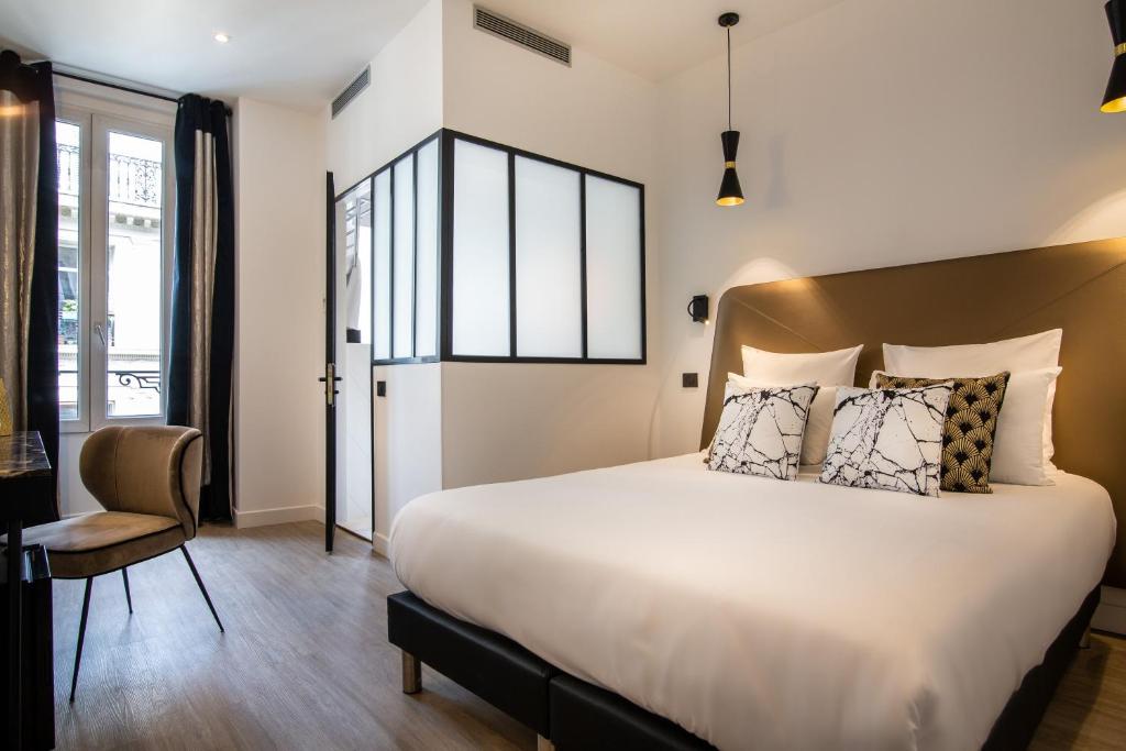 a bedroom with a large bed and a chair at Hôtel Royal Opéra in Paris
