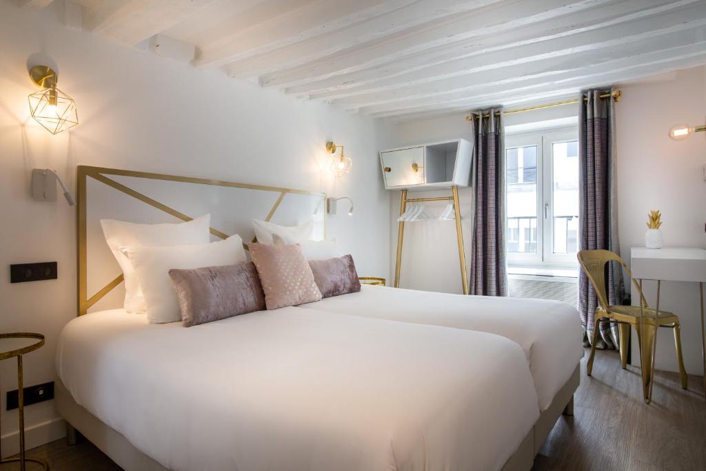 a bedroom with a large white bed with pillows at Hôtel Royal Opéra in Paris