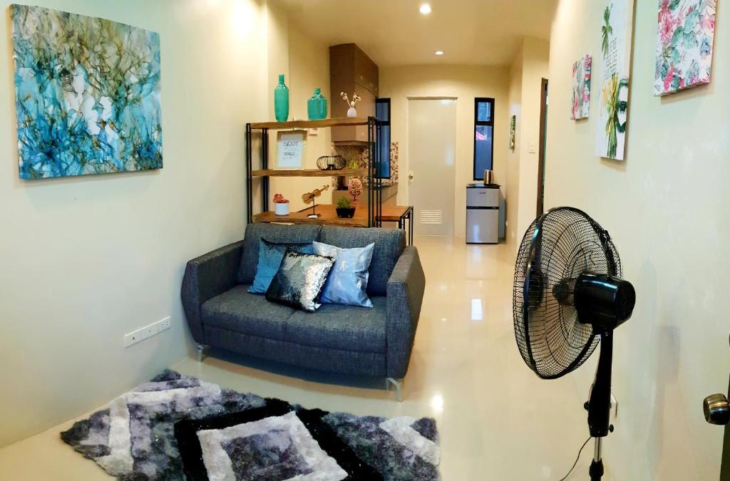 a living room with a couch and a fan at Mailz Haven 7-2BR Apartment in Davao City