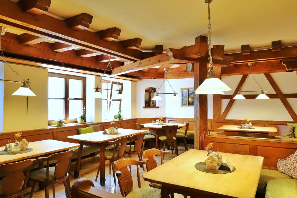 a restaurant with wooden tables and chairs and windows at Pension Adler in Sonthofen