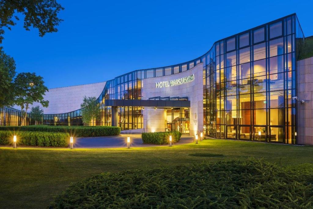 a large glass building with lights in front of it at Hotel Warszawianka in Jachranka