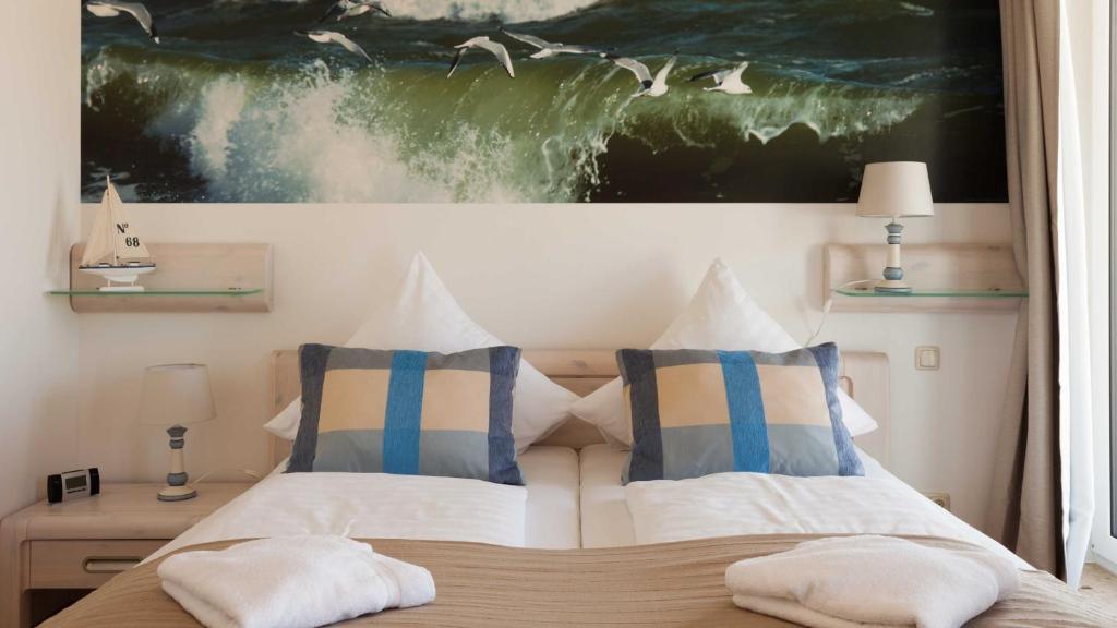 a bedroom with a bed with two pillows and a painting at Villa am Kreidebruch _ Komfort_App in Sassnitz