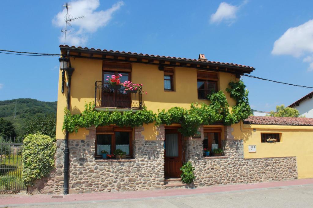 una casa de piedra amarilla con flores en la ventana en Casa Rural Edulis, en Santurde